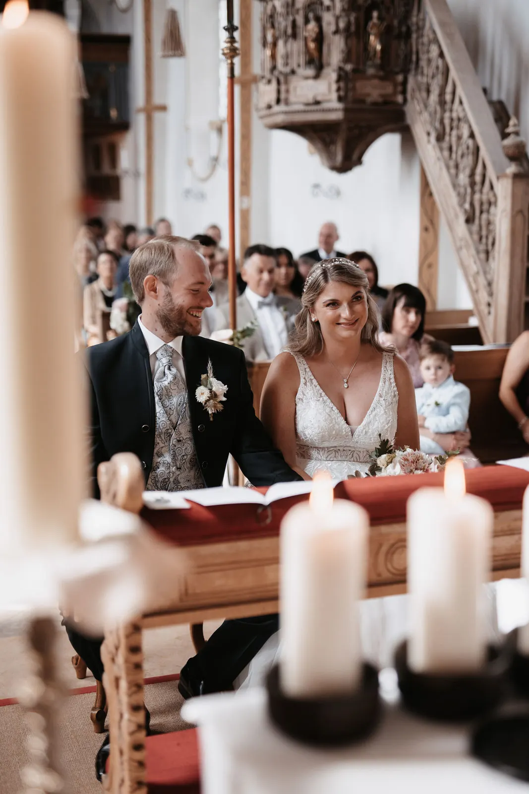 Brautpaar beim Traugottesdienst hinter brennenden Kerzen in Aying